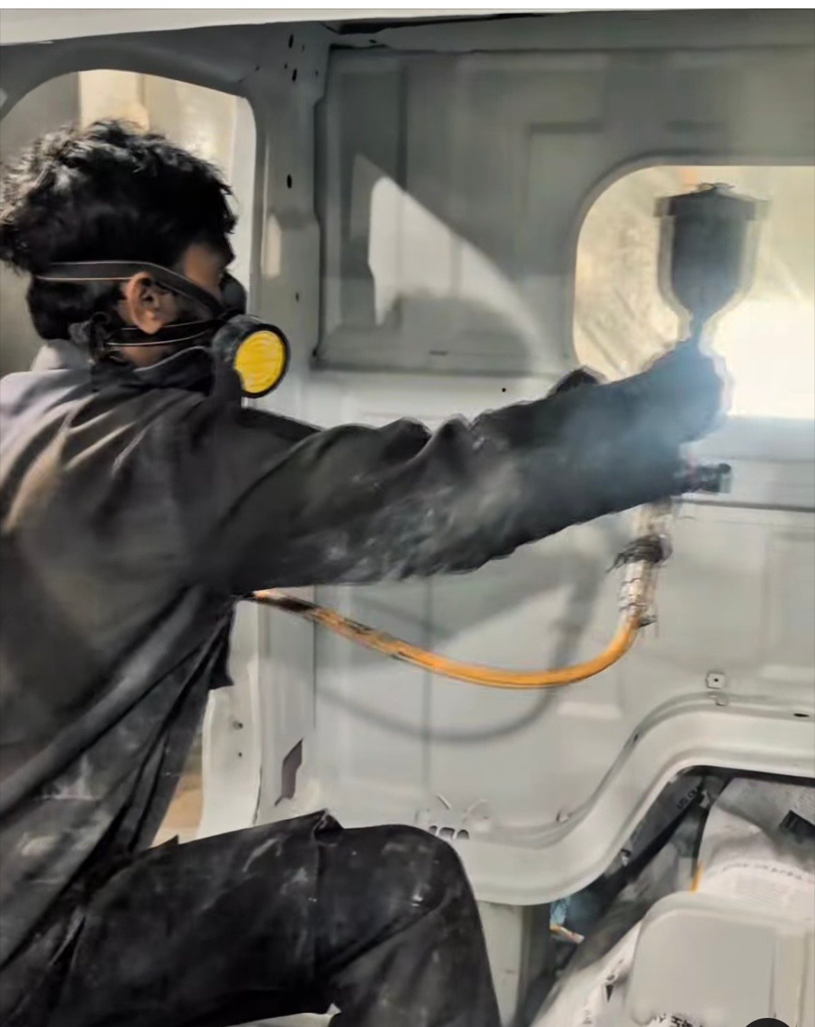 Technician spray painting a vehicle body