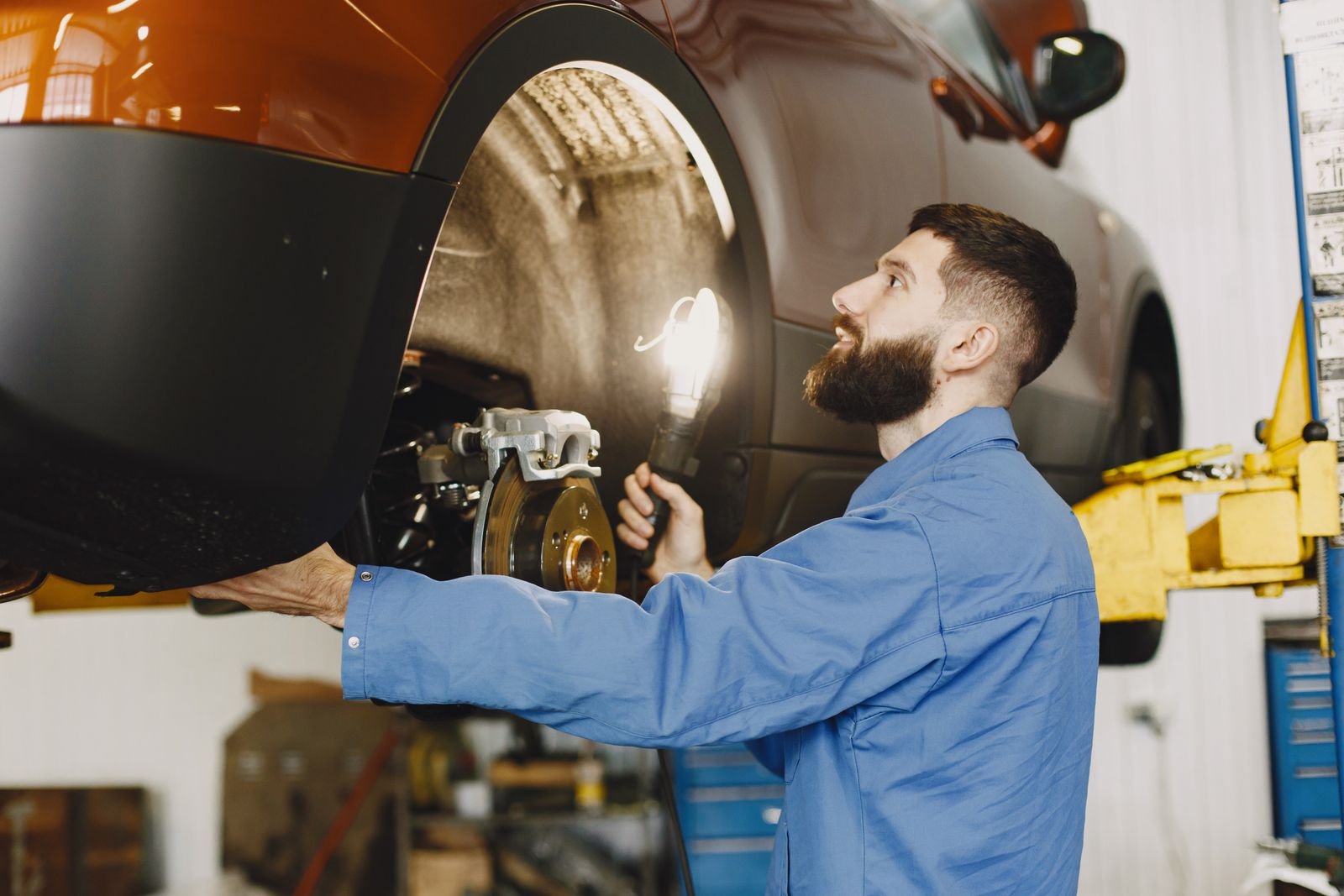Mechanic carefully inspecting a vehicle wheel and brake assembly
